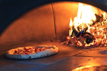 Pizza is baked in the oven near the burning wood. Neapolitan pizzaの写真素材