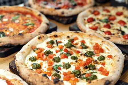 A lot of different freshly prepared pizza on a wooden table in an Italian restaurantの写真素材