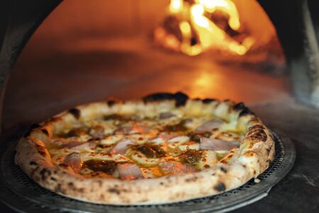 Freshly baked pizza on the background of a burning wood-burning stoveの写真素材