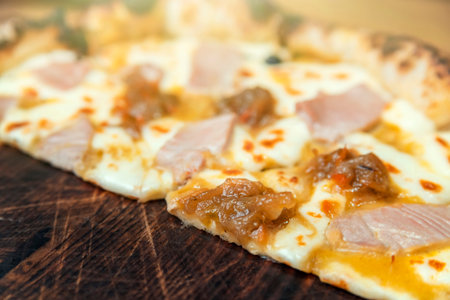 Hot pizza slice with melting cheese on a rustic wooden table.の写真素材