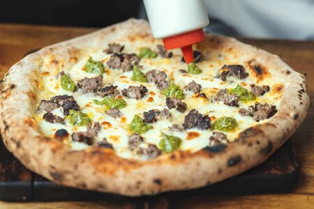 excellent Italian pizza on a wooden table. poured sauceの写真素材