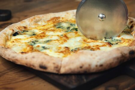 Cutting pizza in close-up. Cook cut pizza with a round knifeの写真素材