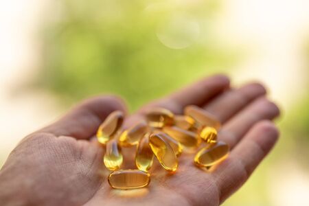 A handful of vitamin d capsules is in a mans hand.の写真素材