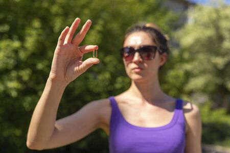 The girl holds the yellow pill with her fingers.の写真素材