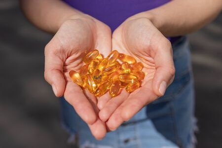 A handful of vitamin d capsules are in women's hands. Blurred backgroundの写真素材