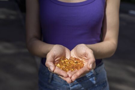 A handful of vitamin d capsules are in women's hands. Blurred backgroundの写真素材