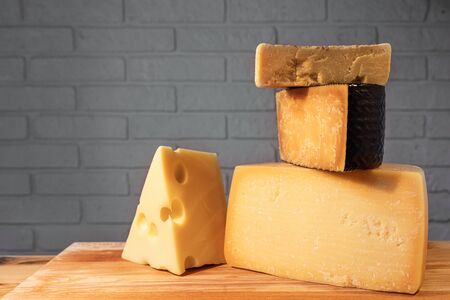 Pyramid of various cheeses on a wooden Board against a brick wall.の写真素材