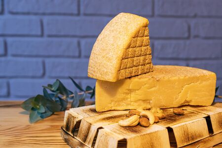 Aged cheese and nuts on a wooden table against a brick wall.の写真素材