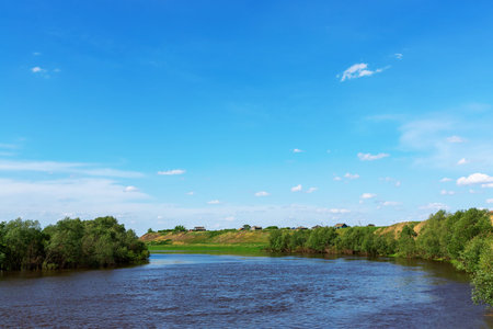 Rural landscape. A narrow river flows between the cliff and the meadow.