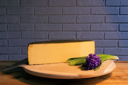 A large piece of aged cheese with spices, next to a purple flowerの写真素材
