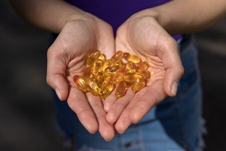 A handful of vitamin d capsules are in women's hands. Blurred backgroundの写真素材