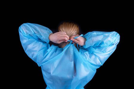 The doctor puts on a protective medical gown. Rear viewの写真素材