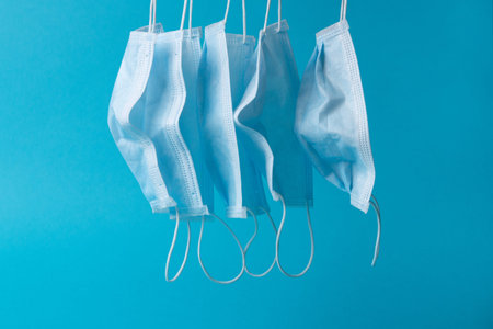 Surgical masks hanging in quarantine resting on blue backgroundの写真素材
