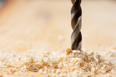 close-up view of a drill bit drilling a wood and chips jumpingの写真素材