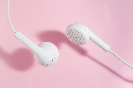 white in ear headphones on a light pink background. Closed top view.