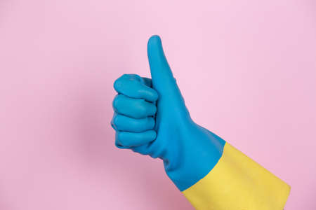 A hand with cleaning gloves making the OK gesture on pink backgroundの写真素材