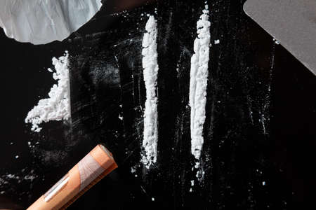 Two Cocaine lines prepared on a table and a rolled banknote ready to be sniffed. Top viewの写真素材