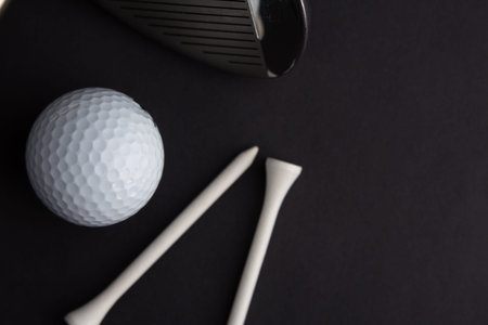golf ball and iron stick seen very close. Black background