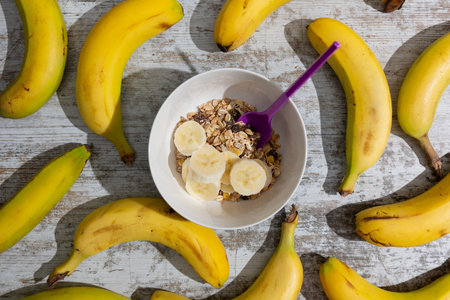 A cup of breakfast prepared with cereals and cut banana. Plants aroundの写真素材
