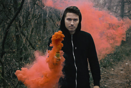 guy with colorful smoke in forest at morning