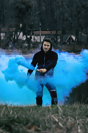 guy with colorful smoke in forest at morningの写真素材