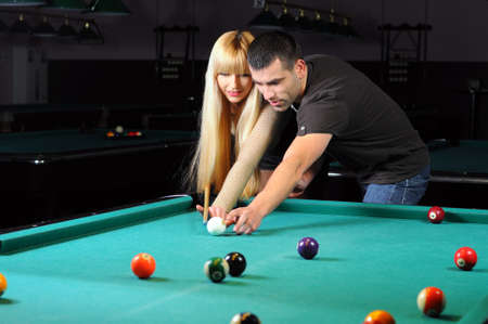 Young couple playing snooker in a billiard clubの写真素材