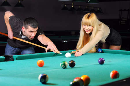 Young couple playing snooker in a billiard clubの写真素材