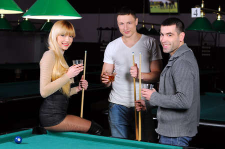 Young attractive people aim at game at billiardsの写真素材