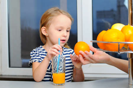 Portrait of happy little girl drinking orange juiceの写真素材