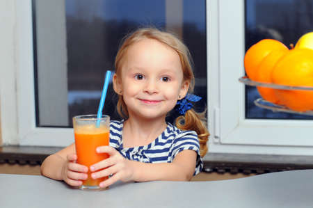 Portrait of happy little girl drinking orange juiceの写真素材