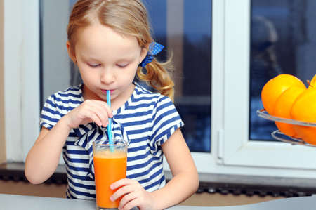 Portrait of happy little girl drinking orange juiceの写真素材