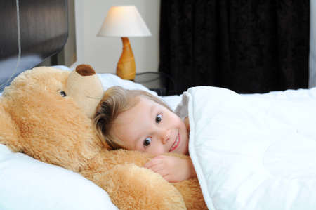 Portrait of cute girl lying in the bedの写真素材