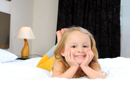 Portrait of cute girl lying in the bedの写真素材