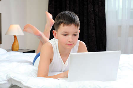 Kid with laptop in bed, happy timeの写真素材