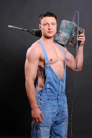 Muscular man with jackhammer on a black backgroundの写真素材