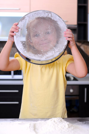 Cute blond little girl making bread in the kitchen