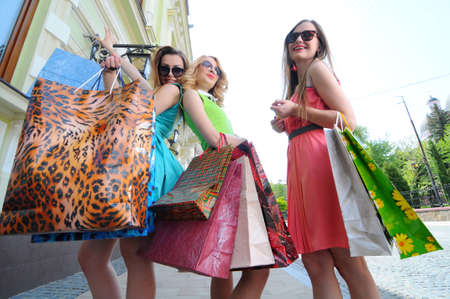 three young women with shopping bags walking in the cityの写真素材