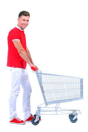 Full length portrait of a man posing next to an empty shopping cart isolated on white backgroundの写真素材