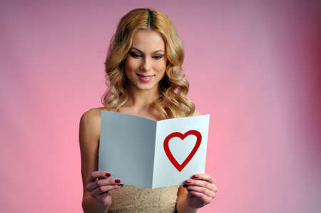 Girl with a greeting card on a pink background  Valentines dayの写真素材