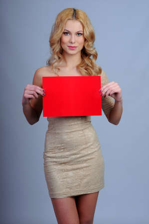 blonde with a red plate in hands on a gray backgroundの写真素材