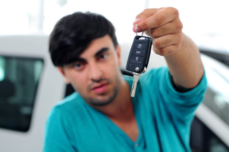 A young man holds the key at the car in the Autoshopの写真素材