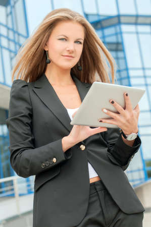 Businesswoman working on digital tablet outdoor over building backgroundの写真素材