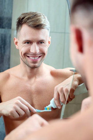 Reflection of a young man in mirror brushing teethの写真素材