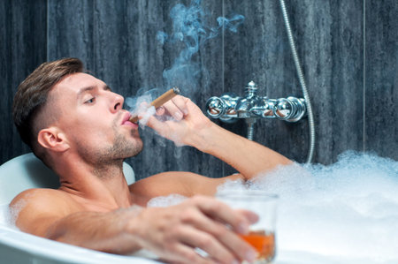 young man taking a bath, drinking whiskey and smoking cigarの写真素材