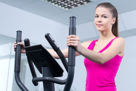 Fitness Woman. Happy woman training at the gym on cross trainer