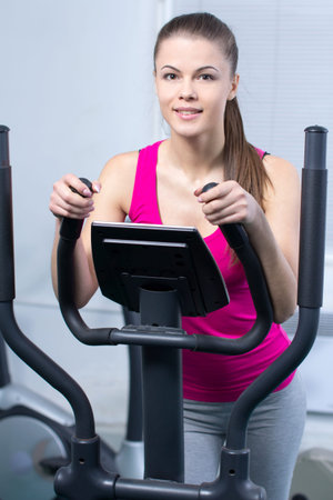 Fitness Woman. Happy woman training at the gym on cross trainer