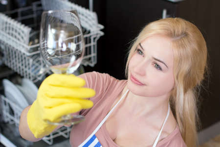 Kitchen Woman. Girl in the kitchen using dishwasher. view of young woman in kitchen doing housework. see clean the glassの写真素材