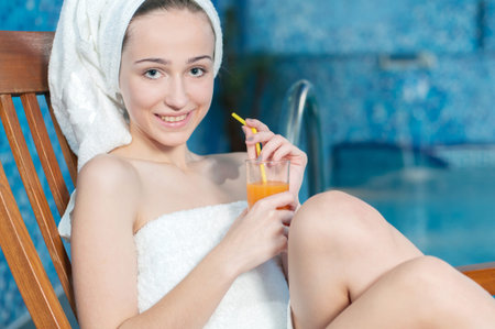Spa & Wellness. Closeup of pretty smiling woman with juice glass in spa salonの写真素材