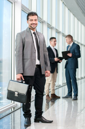 Portrait of a happy asian businessman in a modern office on a background of colleaguesの写真素材