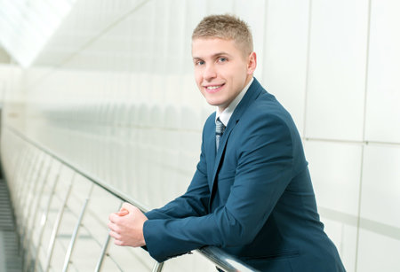 Portrait of a young smiling businessman in a business buildingの写真素材